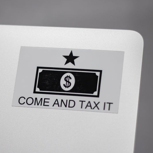 Sticker with a dollar bill design and text 'COME AND TAX IT' on the back of a metallic laptop.